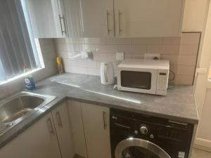 En-suit double bedroom with bathroom in Manchester في مانشستر: مطبخ مع غسالة ملابس وميكرويف