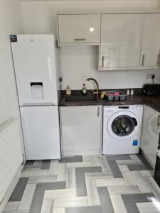 a kitchen with white cabinets and a washing machine at Detached Flat in Leeds, Free WIFI and parking, Pool table, 75 inch tv, Netflix, Disney plus in Moortown