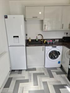 a kitchen with white cabinets and a washing machine at Detached Flat in Leeds, Free WIFI and parking, Pool table, 75 inch tv, Netflix in Moortown +13 photos