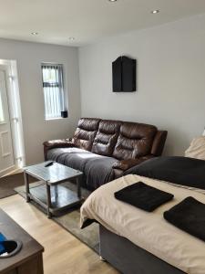a living room with a leather couch and a table at Detached Flat in Leeds, Free WIFI and parking, Pool table, 75 inch tv, Netflix, Disney plus in Moortown