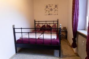 a bedroom with a metal bed with purple sheets at Ferienwohnung auf einem Reiterhof in Weißenstadt