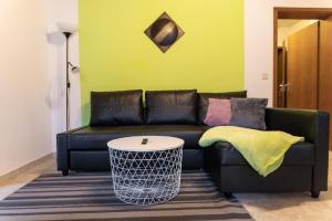 a black leather couch in a living room with a table at Ferienwohnung auf einem Reiterhof in Weißenstadt