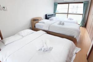 três camas num quarto com lençóis brancos em Itsukaichi First Villa Hiroshima - Vacation STAY 15653 em Hiroshima
