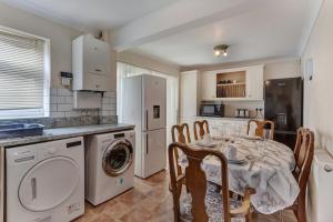 a kitchen with a table and a washer and dryer at Spacious & Centrally Located Home in Basildon With Parking Close to Town Centre in Basildon