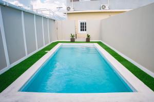 una piscina en el patio trasero de una casa con césped verde en Incognito Reggae Rooms en Kingston