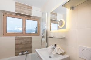 a white bathroom with a sink and a shower at Familienappartement Seenland in Reith im Alpbachtal
