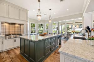 a large kitchen with white cabinets and a green island at Peaceful Country Charm with Private Pool in Dripping Springs