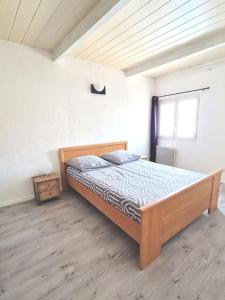 - une chambre avec un lit en bois dans l'établissement Maison à 9 minutes de la plage, à Bompas