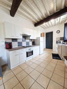 a kitchen with white cabinets and a tile floor at Maison à 9 minutes de la plage in Bompas