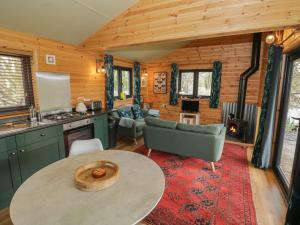 eine Küche und ein Wohnzimmer mit einem Tisch in einer Hütte in der Unterkunft Kingfisher in Rugby