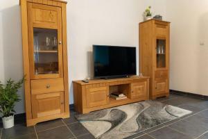 TV en un centro de entretenimiento de madera con armario en Ferienwohnung im ersten Obergeschoss en Weißenstadt