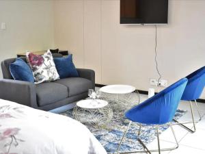 sala de estar con sofá y sillas azules en Lea's Furnished Apartments - Lofts at Loftus en Pretoria