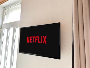 un televisor con la señal de netflix en una pared en L'Eden Carolo - Netflix, Wi-Fi, 10min Aéroport, Parking gratuit en Dampremy