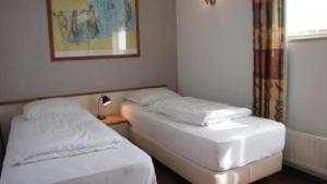 2 camas individuales en una habitación con ventana en Bungalows für vier Personen, direkt am Strandbad gelegen, en Oostrum