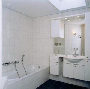 Baño blanco con bañera y lavamanos en Bungalows für vier Personen, direkt am Strandbad gelegen, en Oostrum