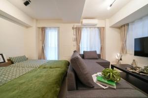een slaapkamer met een bed, een bank en een tv bij Mondomio Sapporo Minamisanjo Dori - Vacation STAY 16325 in Sapporo
