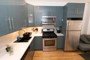 a kitchen with blue cabinets and stainless steel appliances at Close to NYC - Stylish Modern Studio in Union City