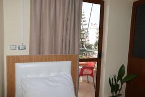 クサミルにあるGusto Hotelのベッドルーム1室(ベッド1台、窓、椅子付)