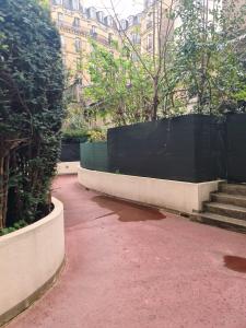 a brick walkway with a black fence and stairs at Appartement Jasmin 16ème in Paris