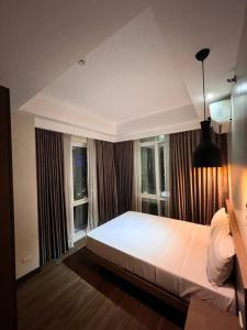 - une chambre avec un grand lit et 2 fenêtres dans l'établissement Monarch Suites at Padgett Cebu w/ pool near Ayala, à Cebu
