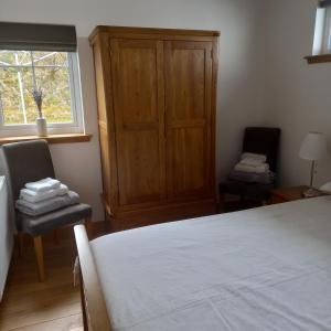 a bedroom with a bed and two chairs and a window at Keistle Cottage in Eyre