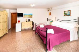 a bedroom with a large bed with a pink blanket at Hotel Fernanda in Letojanni