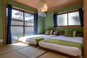 2 Betten in einem Zimmer mit grünen Wänden und Fenstern in der Unterkunft Satorie Beppu - Vacation STAY 19669v in Beppu