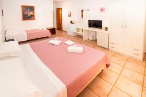 a large room with two beds and a television at Hotel Fernanda in Letojanni