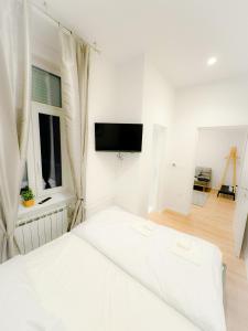 Apartman No. 3 في زغرب: غرفة نوم بيضاء مع سرير وتلفزيون بشاشة مسطحة