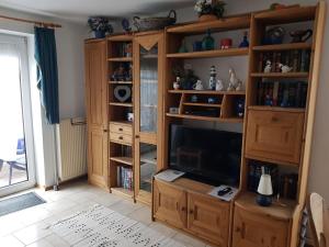 a living room with a tv and a book shelf at Ferienhaus in Neßmersiel mit Großer Terrasse in Dornum