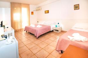 a hotel room with two beds and a refrigerator at Hotel Fernanda in Letojanni