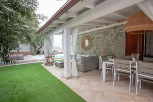 a patio with a table and chairs and grass at Villa Coclea con piscina in San Teodoro