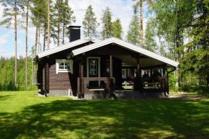 a small cabin in the middle of a grass field at Hochwertiges Ferienhaus mit Sauna sowie Holzterrasse und Garten am See in Sotkamo