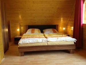 ein Schlafzimmer mit einem Bett mit einer Holzwand in der Unterkunft Harzer Blockhaus III in Bad Sachsa