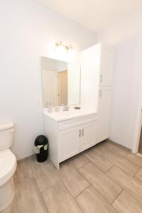 Baño blanco con lavabo y aseo en Quaint Two-Bedroom Abode mins to NYC, en Jersey City
