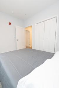 a white bedroom with a large bed with white cabinets at Quaint Two-Bedroom Abode mins to NYC in Jersey City