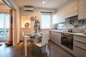 a kitchen with a table with white chairs and a table and a kitchen with at Appartement in Naxos - b58780 in Giardini Naxos