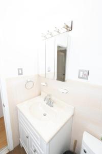 a white bathroom with a sink and a mirror at Close to NYC - Welcoming & Friendly 2-Bed Home in Union City