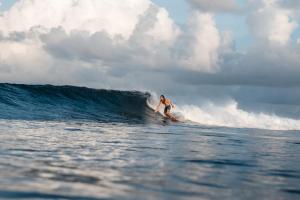 a man riding a wave on a surfboard in the ocean at The Zen Den in Thulusdhoo