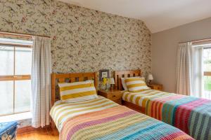 two beds in a room with floral wallpaper at Grove Fort Self Catering Farmhouse in Finnis