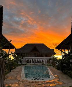 a pool in front of a building with a sunset at Nadia&Ale House - Maisha Resort in Watamu
