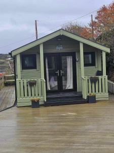 una pequeña casa verde con porche y puerta en Sea Breeze cabin en Donegal