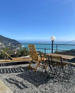 a wooden table and chairs sitting next to the ocean at Agriturismo L'Ulivo E Il Mare in Moneglia