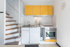 a small kitchen with yellow cabinets and a staircase at Ferienhaus Teichblick in Klütz