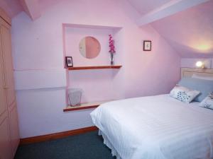 een slaapkamer met een wit bed en een spiegel bij Sheans Holiday Cottage Killarney by Trident Holiday Homes in Killarney