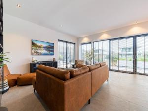 a living room with a brown couch and windows at Water villa with its own jetty near Harderwijk in Zeewolde