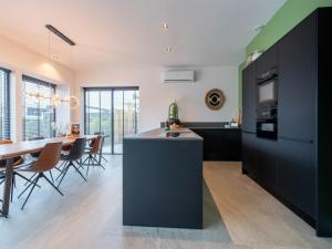 een keuken met zwarte kasten en een eetkamer met een tafel bij Water villa with its own jetty near Harderwijk in Zeewolde