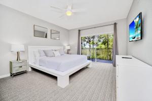 - une chambre blanche avec un lit et un balcon dans l'établissement Near Disney - 3BR Condo - Games Pool & Sauna, à Orlando