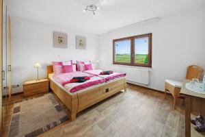 um quarto com uma cama com almofadas cor-de-rosa e uma janela em Ferienhaus in Roggendorf Haus - Fernblick em Mechernich