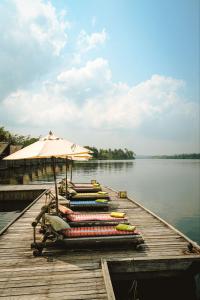 a dock with chairs and an umbrella on the water at Thansur Tatai Eco Resort in Tatai